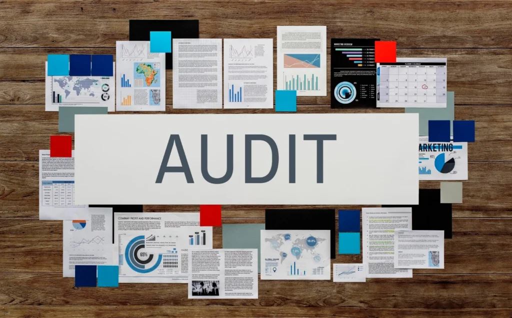 Un grand tableau avec divers graphiques, diagrammes et documents colorés entourant une bannière blanche centrale intitulée « AUDIT ».